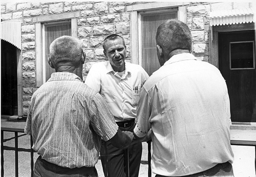 One man looks at the camera while two men have their backs turned